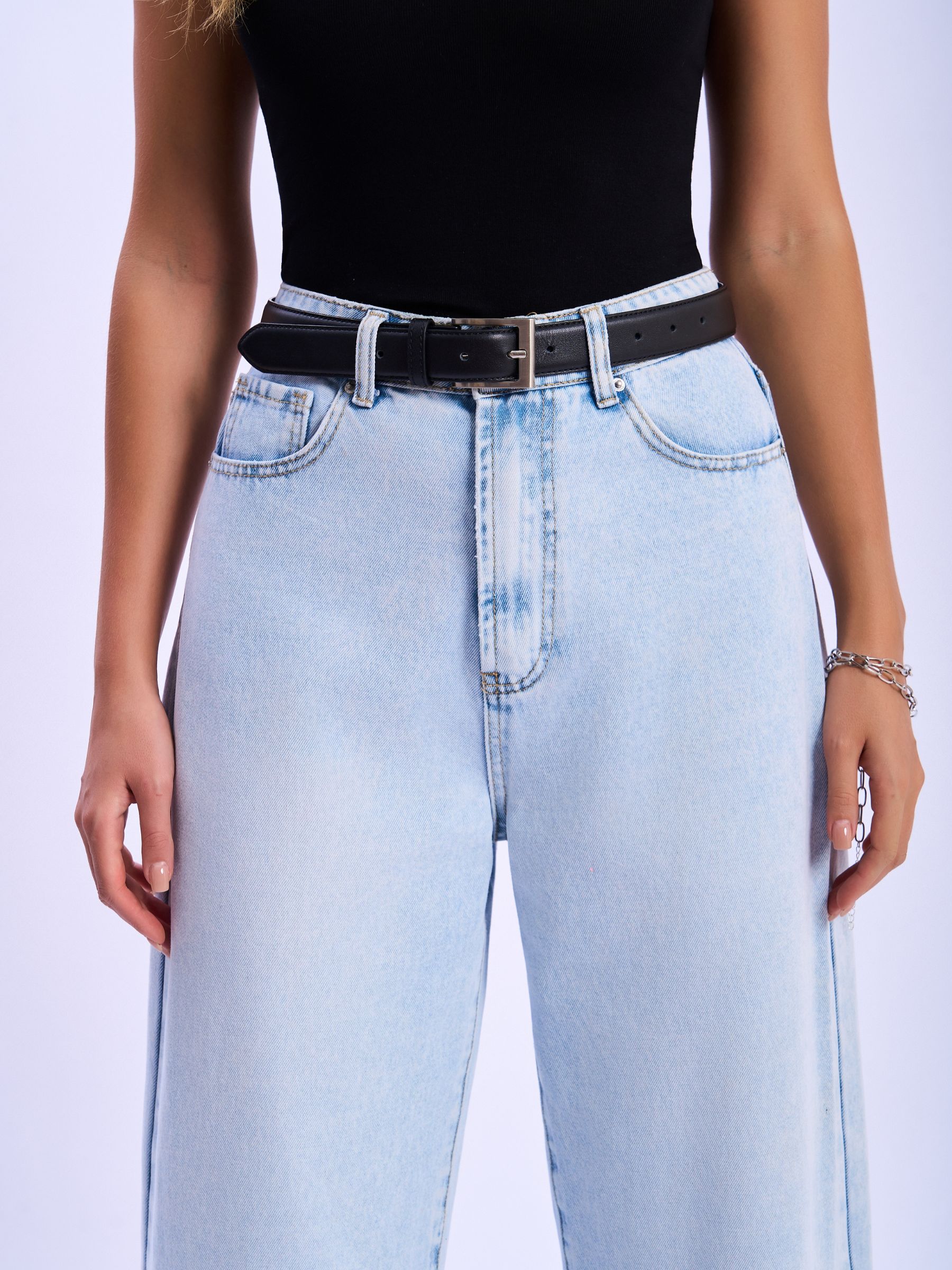Person wearing light blue jeans and a black top on a white background