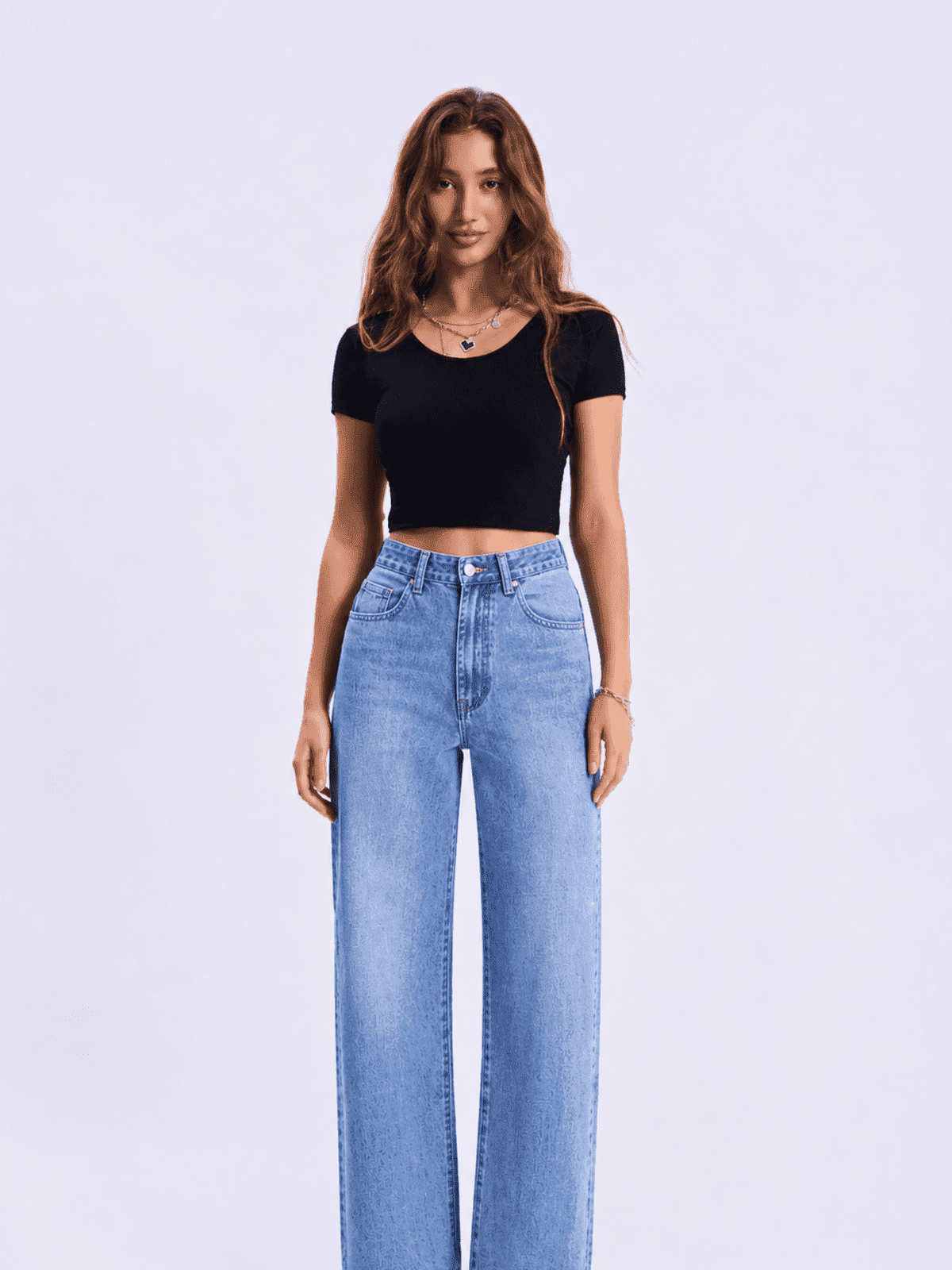 Woman wearing a black crop top and blue jeans on a light gray background