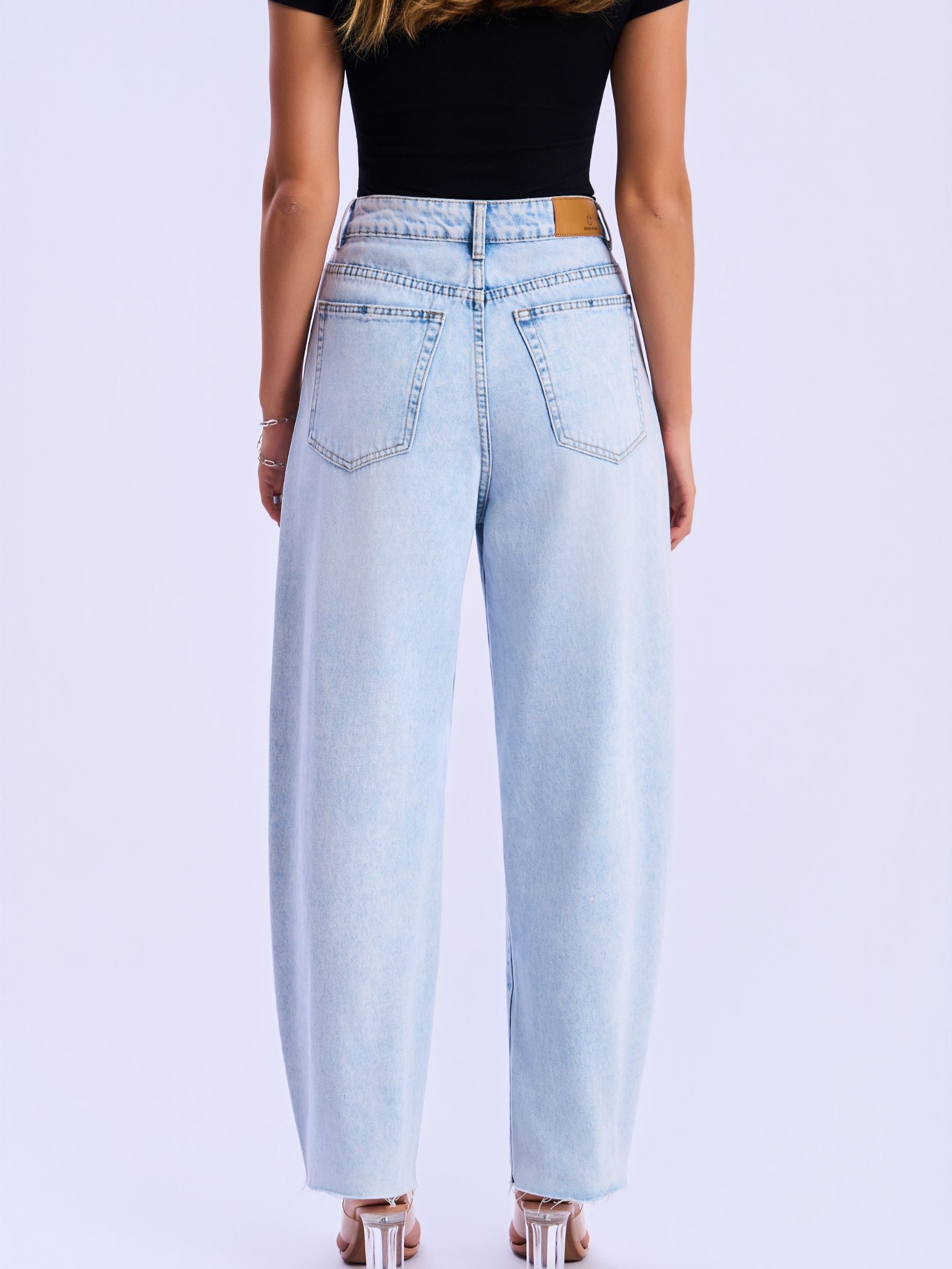 Light blue wide-leg jeans worn by a person on a light purple background