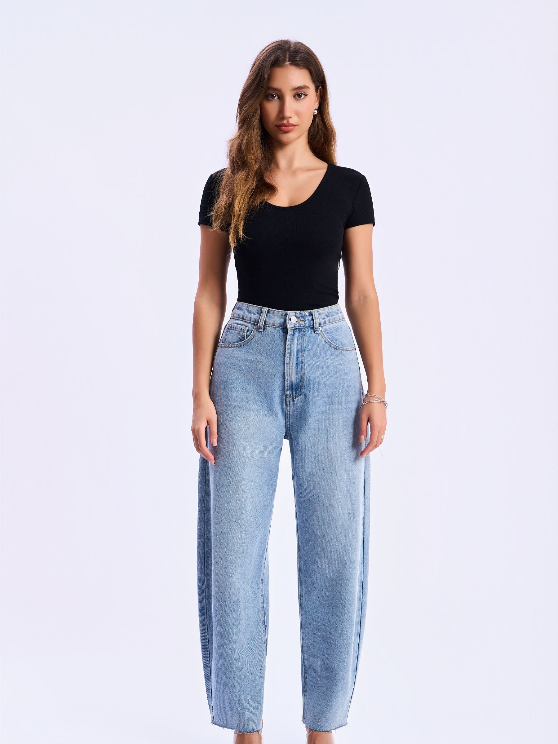 Woman wearing light blue jeans and a black top on a white background