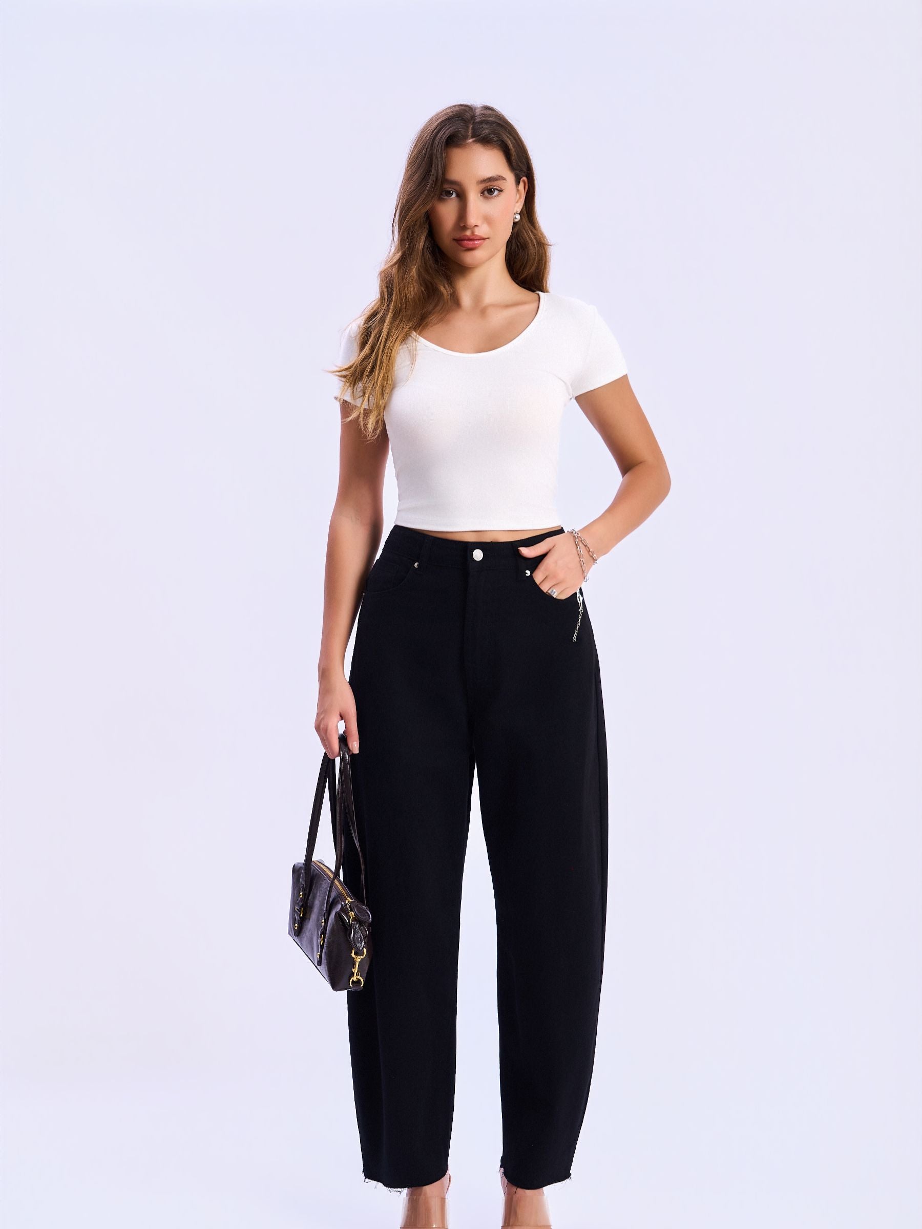 Woman wearing a white top and black pants holding a handbag on a light purple background